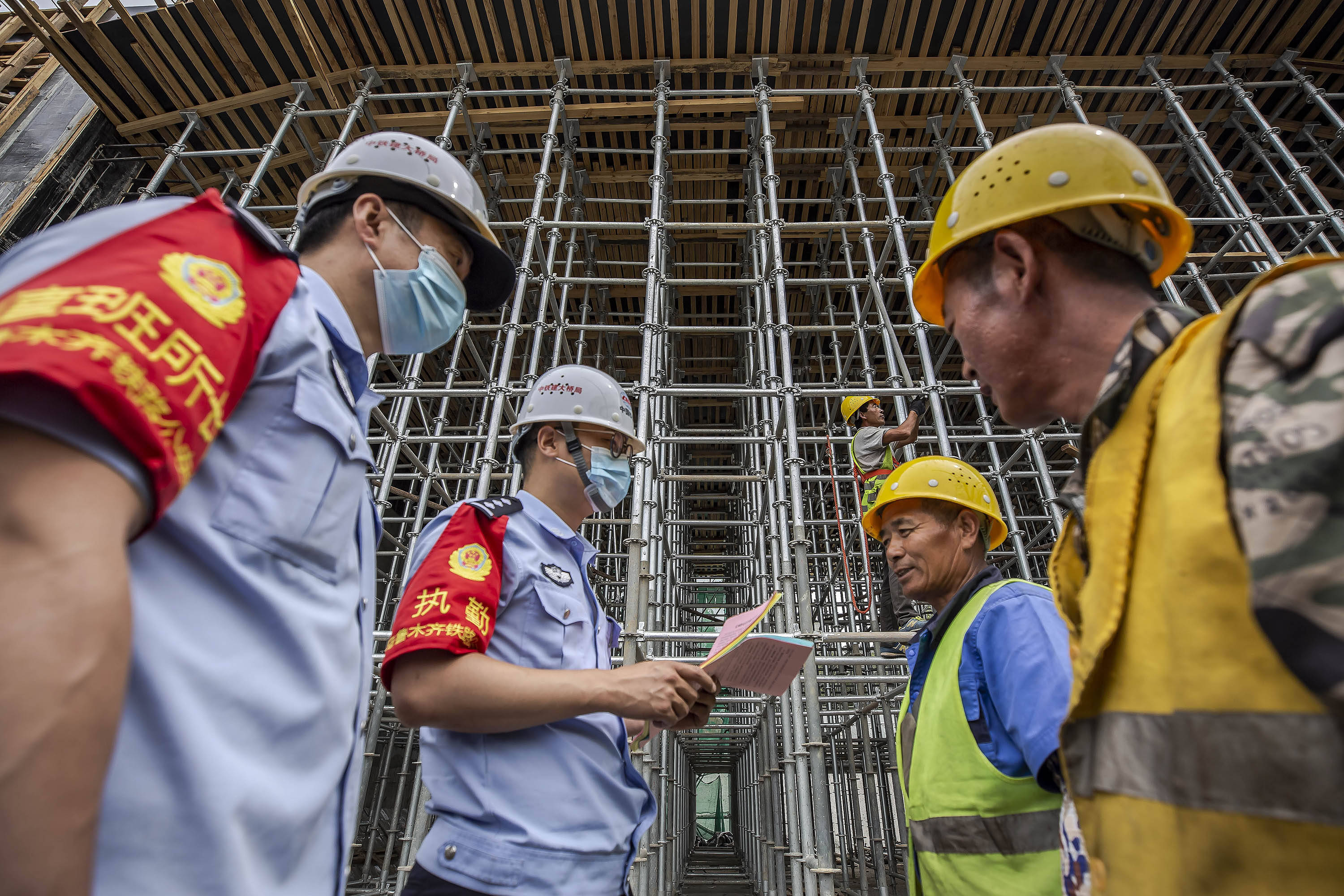 民警在铁路桥涵施工现场向施工人员发放安全生产宣传单.