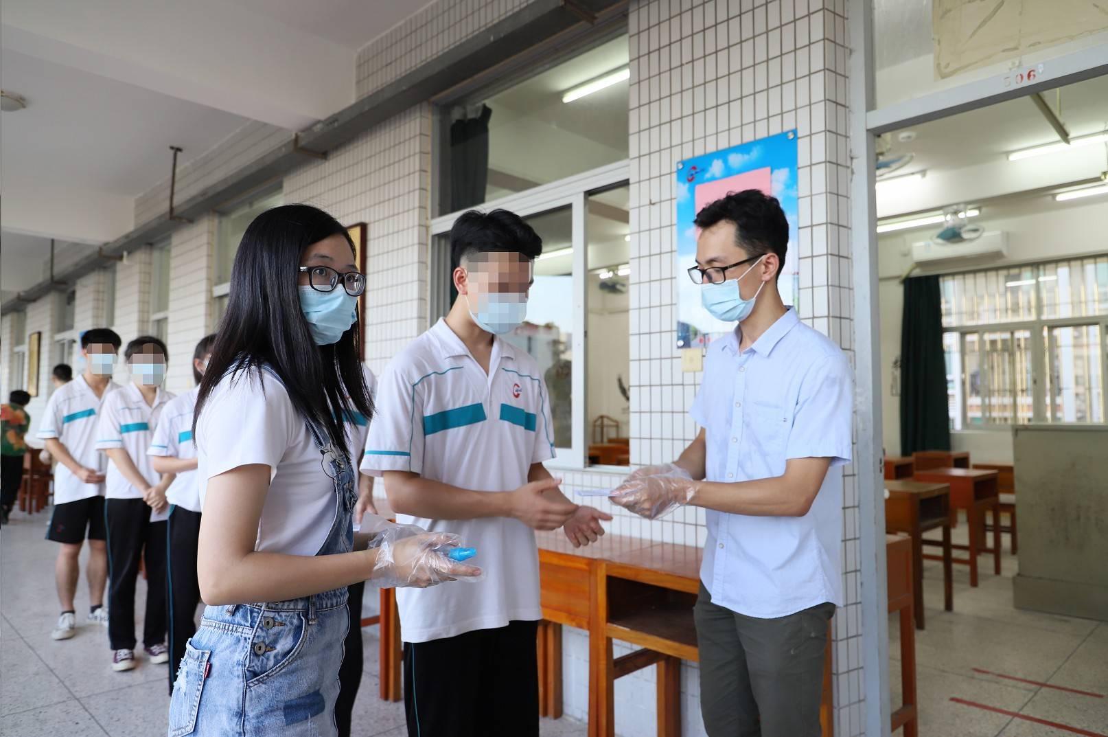 (监考老师检查考生随身物品;图来自翠英中学高考疫情模拟演练)