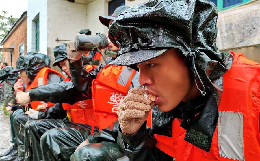 抗洪一线的武警:在雨中进食 累了就躺在堤坝上休息