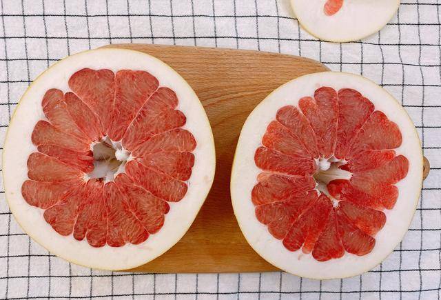 2,把去掉两头的柚子再从中间横切开一刀,把柚子分成2个半圆,这样能