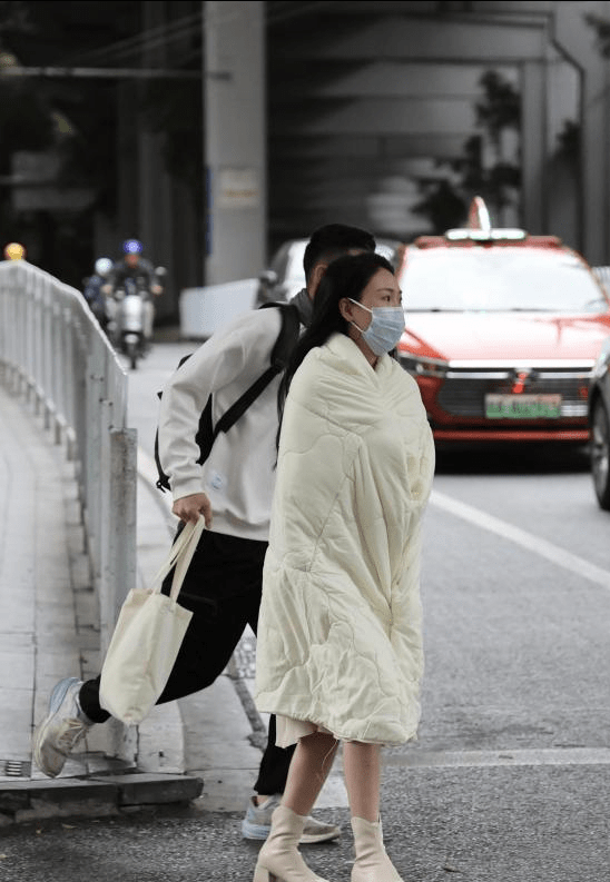 原创当寒潮袭来时，广州街头穿着裙子的小姐姐裹着羽绒被，网友惊呼：太难了！