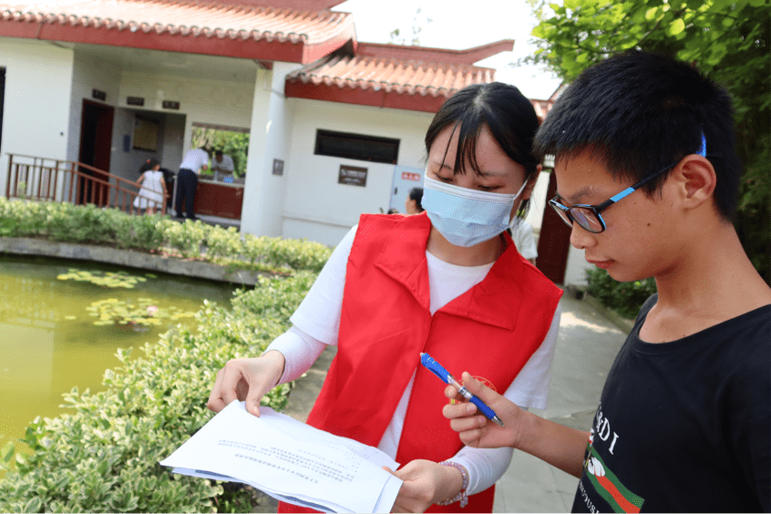 图为实践团成员在与中学生交流日常生活中的普通话使用情况并填写调查