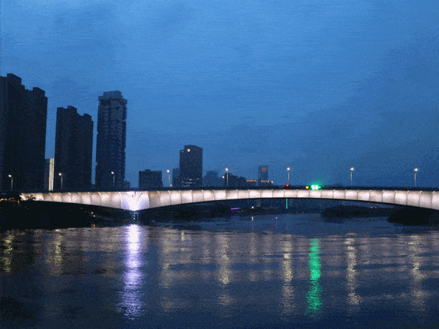 微风拂面,天色渐暗中,沿岸的灯光纷纷亮起,远处的城市显露出缤纷色彩