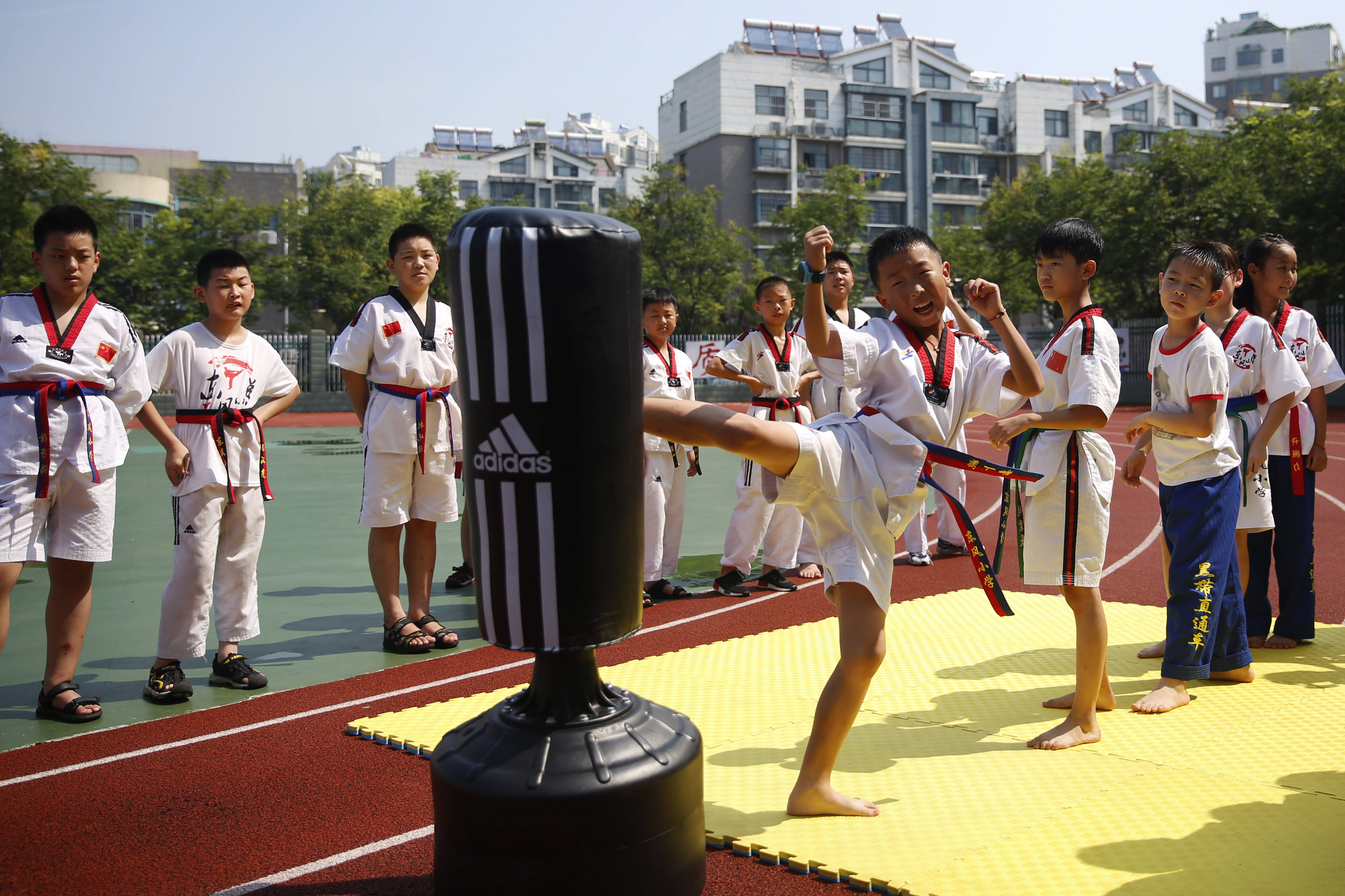 8月1日,泗洪县东风小学跆拳道培训班的学生在进行踢沙袋训练.