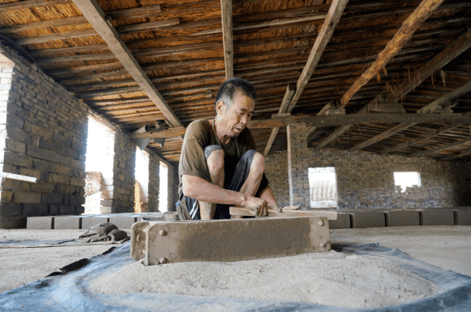 7月30日,河北省任丘市出岸镇古建砖厂工人在清理制作砖坯所用的模具