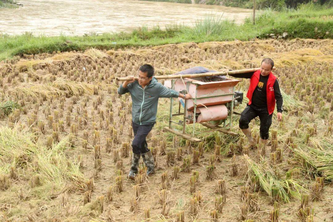 在贵州省榕江县兴华乡高旧村,两名驻村扶贫干部在帮村民搬运打谷机