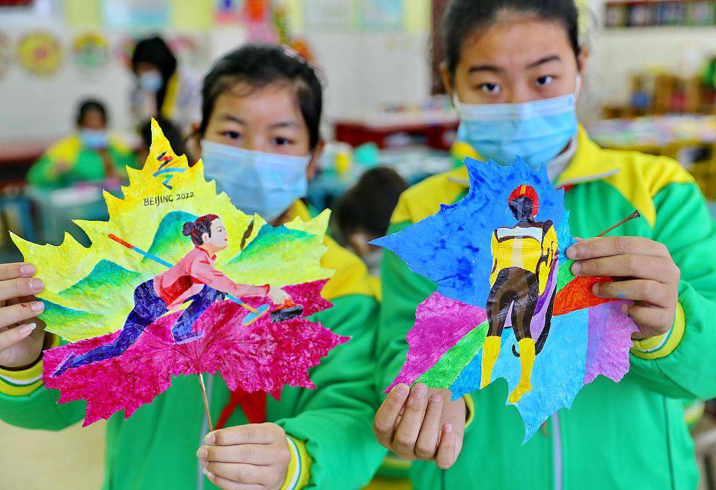 小学生展示自己创作的彩绘树叶冬奥主题作品.(来源:视觉中国)