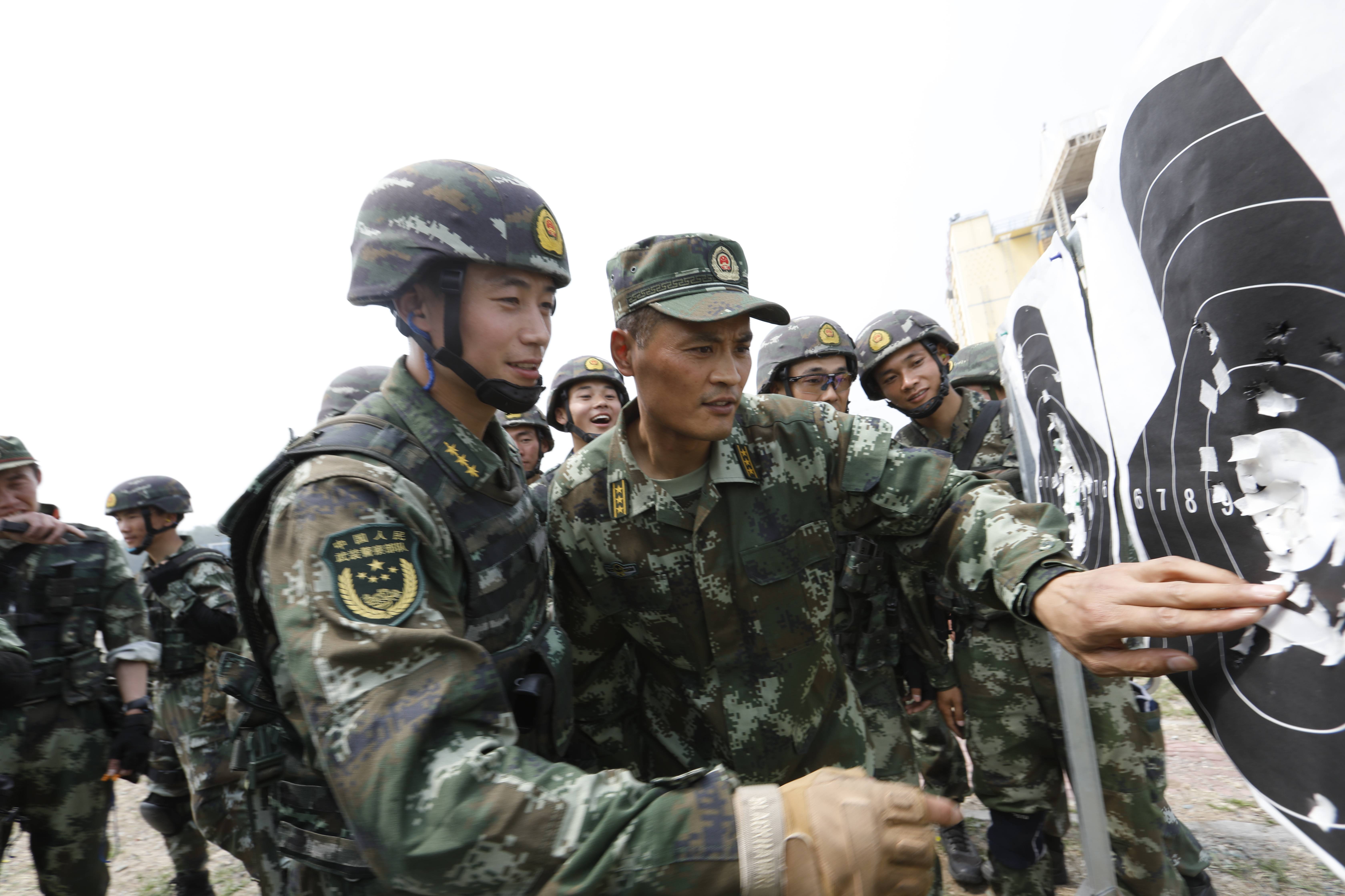 武警猎鹰突击队支队长米彦广(前右一)在训练场与战友探讨射击技巧