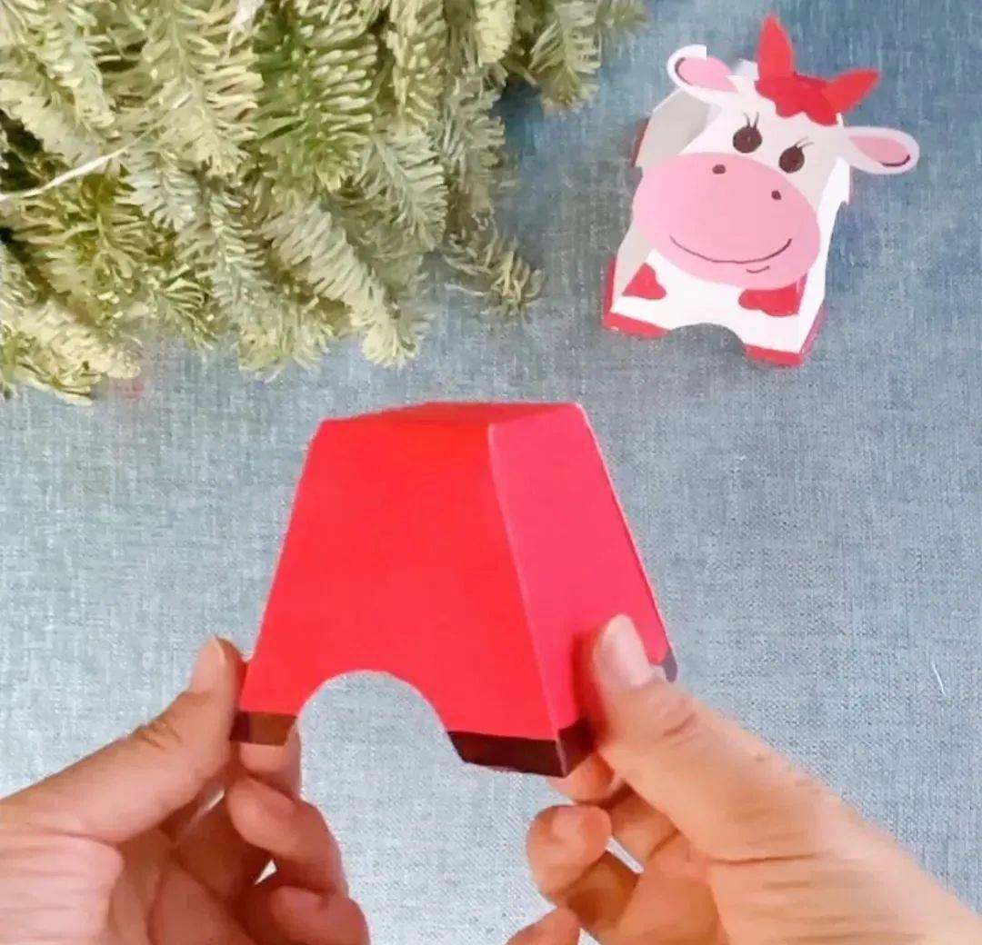 用红色卡纸剪出牛头的形状,贴上一对牛角,耳朵,牛鼻子及动动眼球,并剪