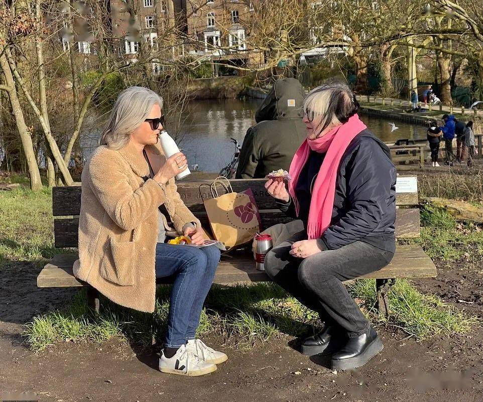 在伦敦汉普斯特希思(hampstead heath),人们坐在长椅上聊天