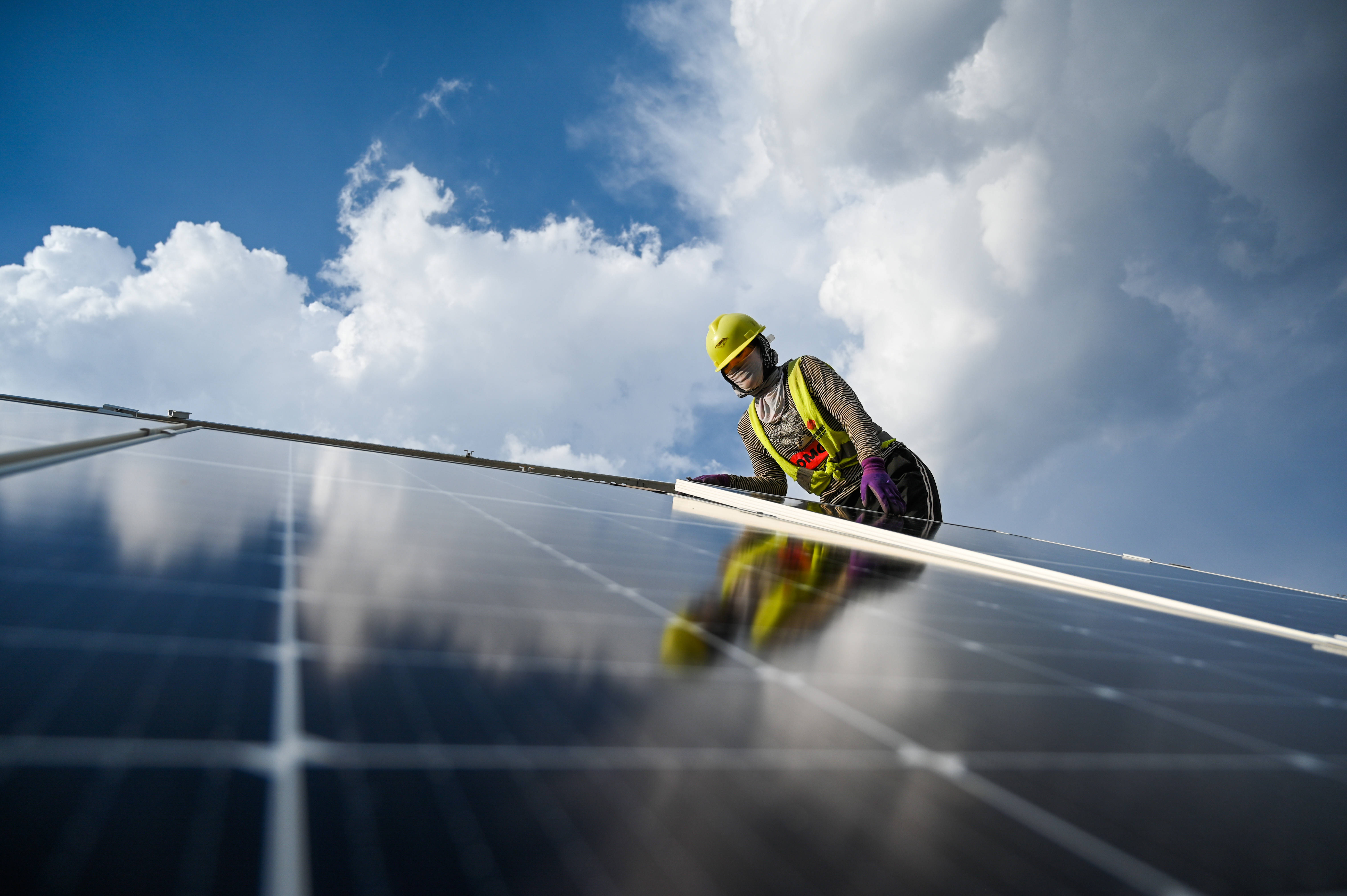 7月13日,一名工人为天骄绿能50万千瓦光伏发电项目安装光伏板.