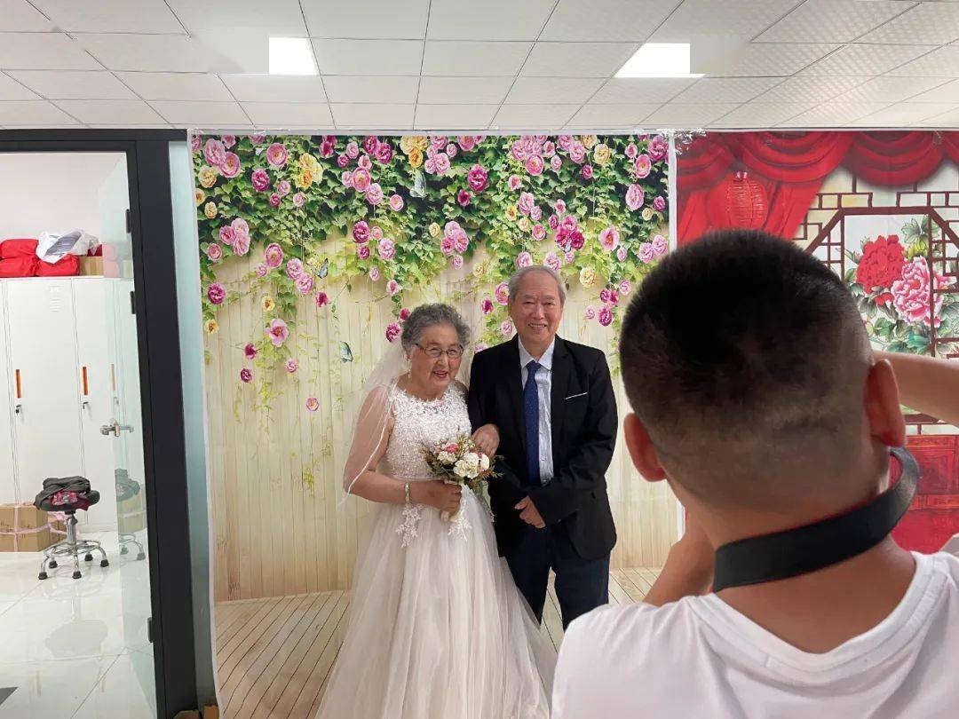 面对镜头,摄影师耐心地指导老人变换拍照姿势,老人们双手紧紧握在一起