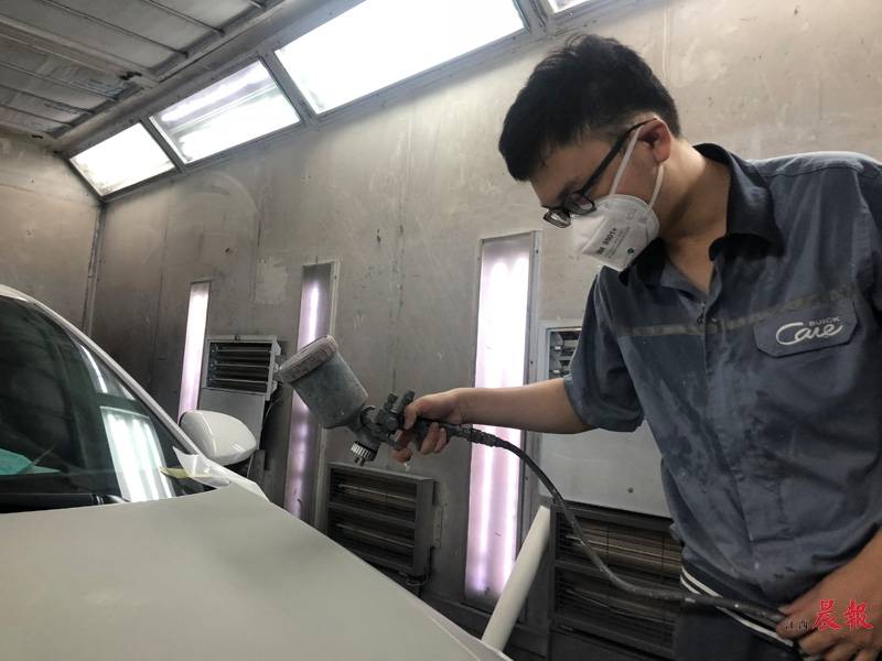 陈世文正在烤漆房里进行喷漆作业.