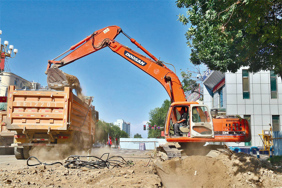 8月30日,在博乐市青得里大街改扩建工程施工现场,工人正在清运土方.