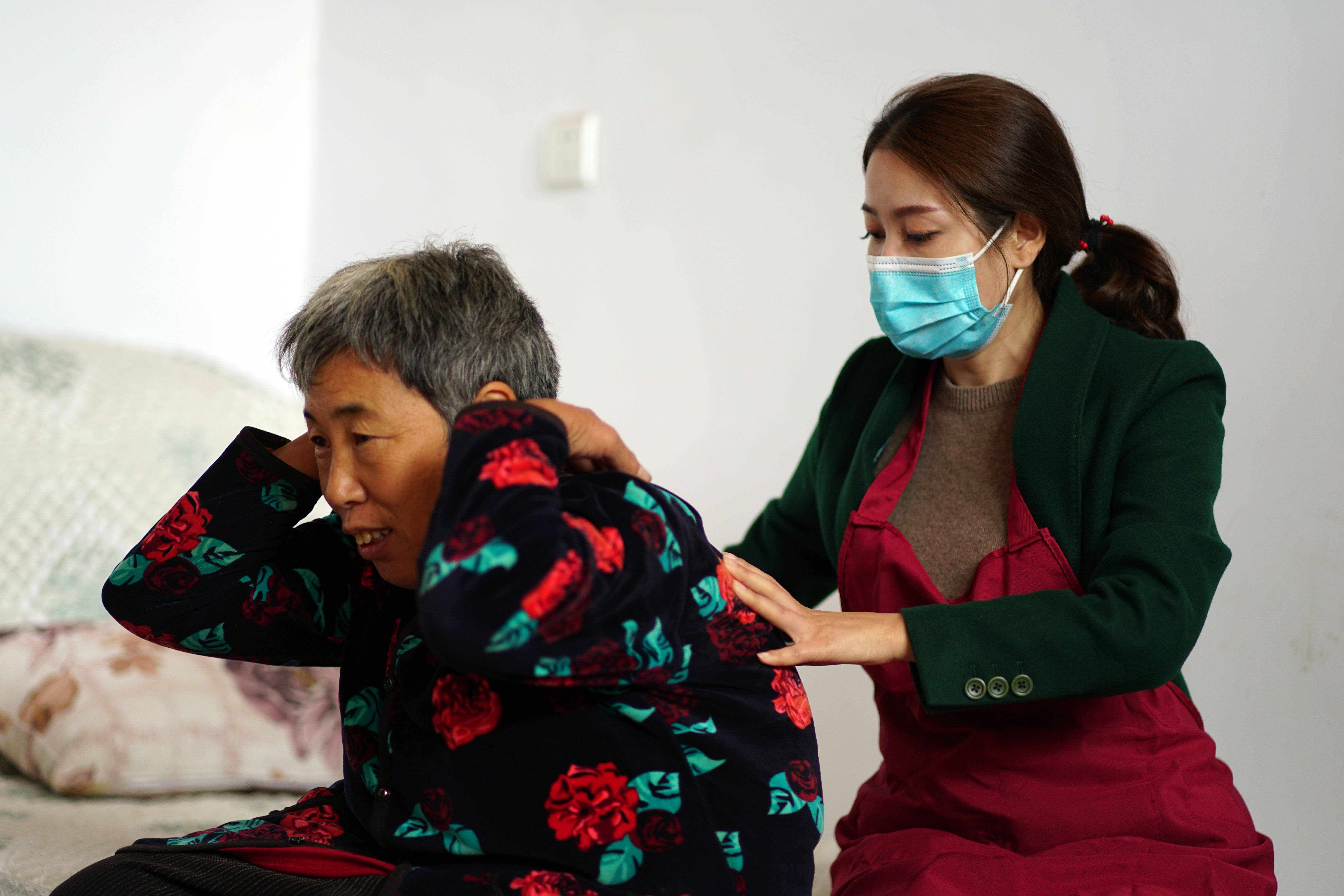10月11日,赵娜(右)在邢台市信都区一户居民家中为老人按摩.