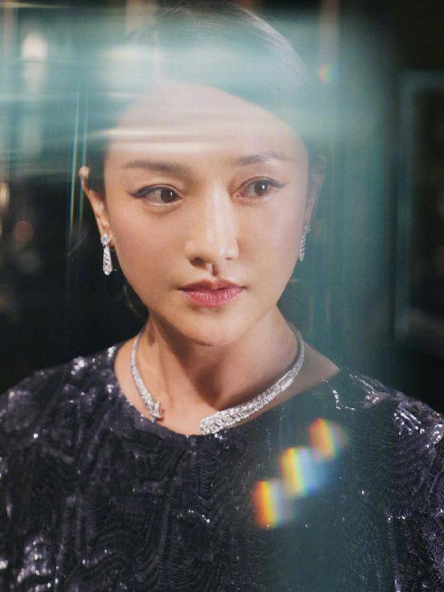 本人周迅纯黑亮片衫神情严肃，一展优雅成熟气质，上挑眼线更添娇媚