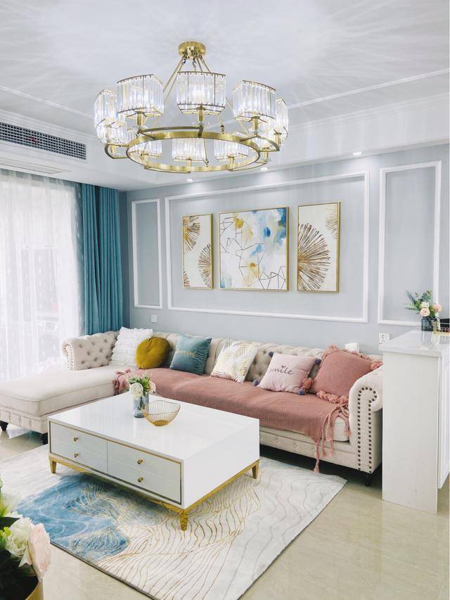 沙发背景墙用白色的石膏线做了简单的造型,搭配着浅灰色的墙面和金边
