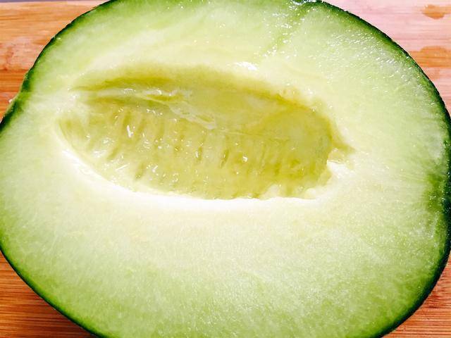 将哈密瓜放在案板上,用刀从中间切开两半.