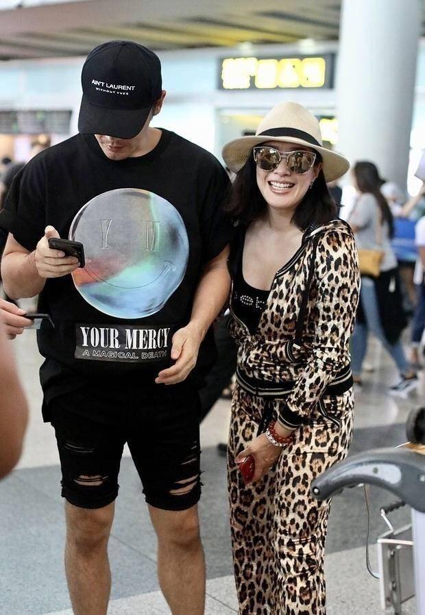 经典|49岁钟丽缇机场高调秀恩爱，却被59岁婆婆抢镜，穿格纹大衣太有范