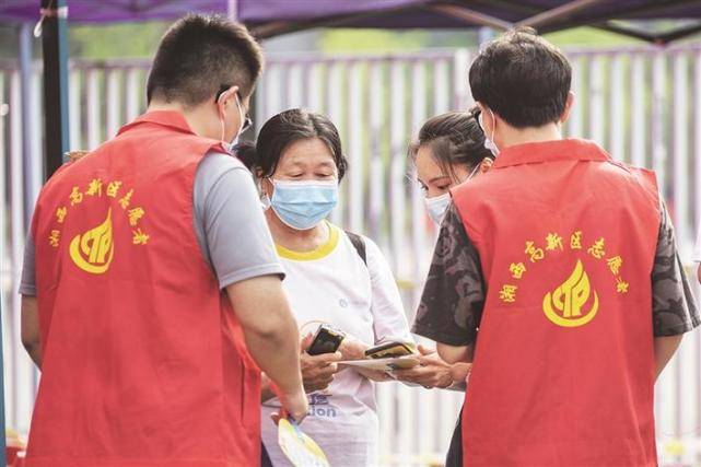 志愿者在帮助不会操作智能手机的老人进行"双码"核验. 明克林 摄