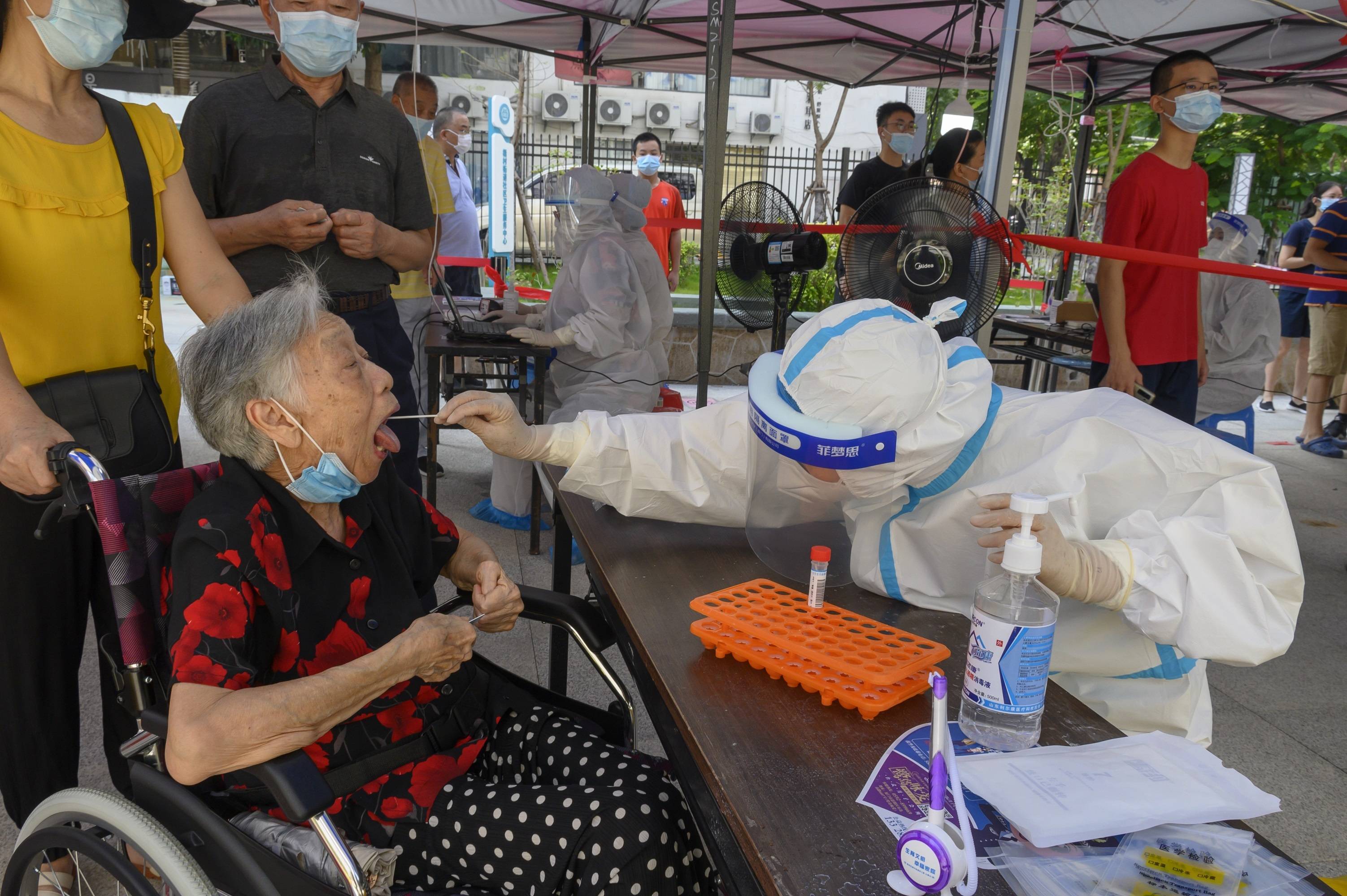 "采样工作人员认真地为老人进行核酸检测采样,银发老人努力张嘴积极