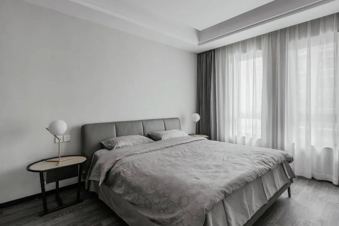 卧室以浅灰色的墙面空间,搭配灰色窗帘,床与床单,带来一种简洁安静