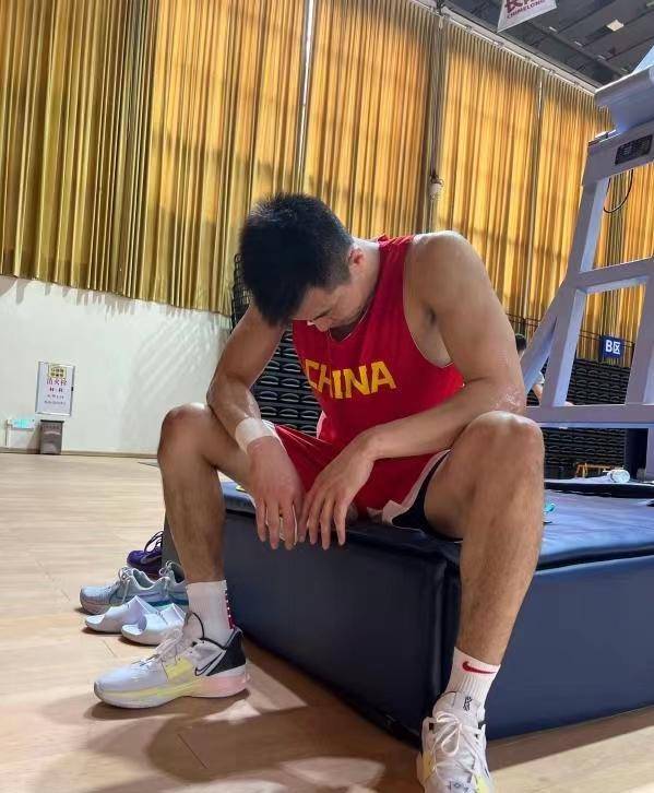 照片中郭艾伦应该是在室内的篮球场里,他穿着红色的球服,正坐着休息.