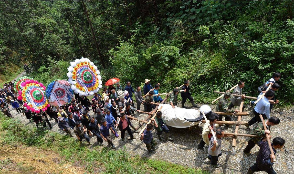 走在出殡队伍最前方的人举着牛王这一生的荣誉,他们的手中举着锦旗或