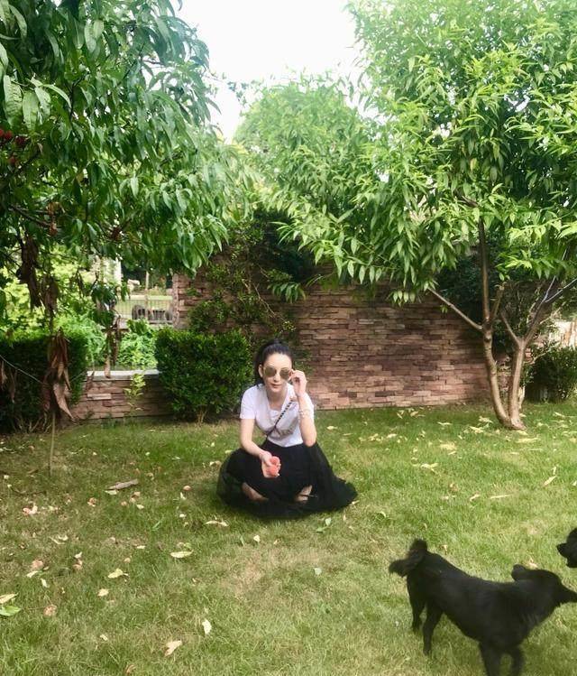 方媛坐在草地上逗身边的两只小黑狗,享受大自然的气息.