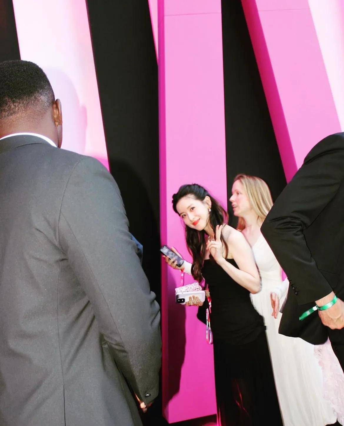 照片中,章泽天扎着公主头,身穿黑色抹胸礼服,手拿粉色小包,一身造型