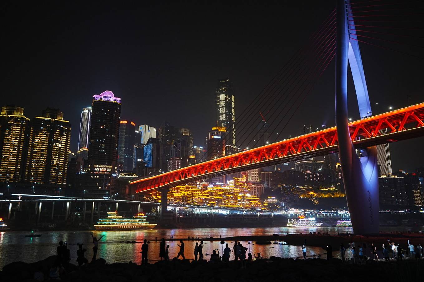 洪崖洞,嘉陵江上的游轮,江岸边玩耍的人们,一幅色彩丰富的夜景画卷