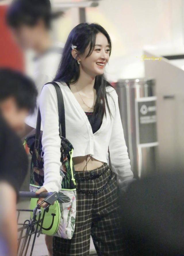 赵丽颖穿着白色短款针织衫内搭黑色吊带,下面搭配着深色格子长裤,黑