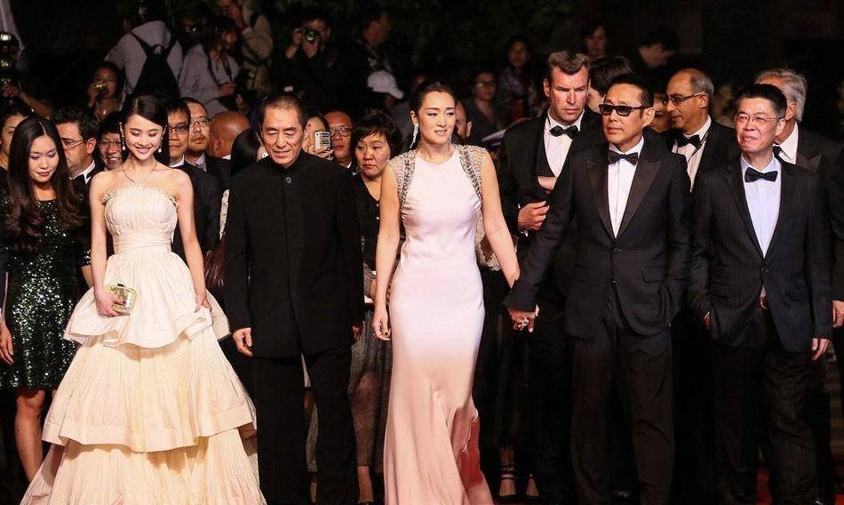 巩俐和陈道明身着优雅的白色礼服,手牵手走上红地毯,张艺谋无奈一笑