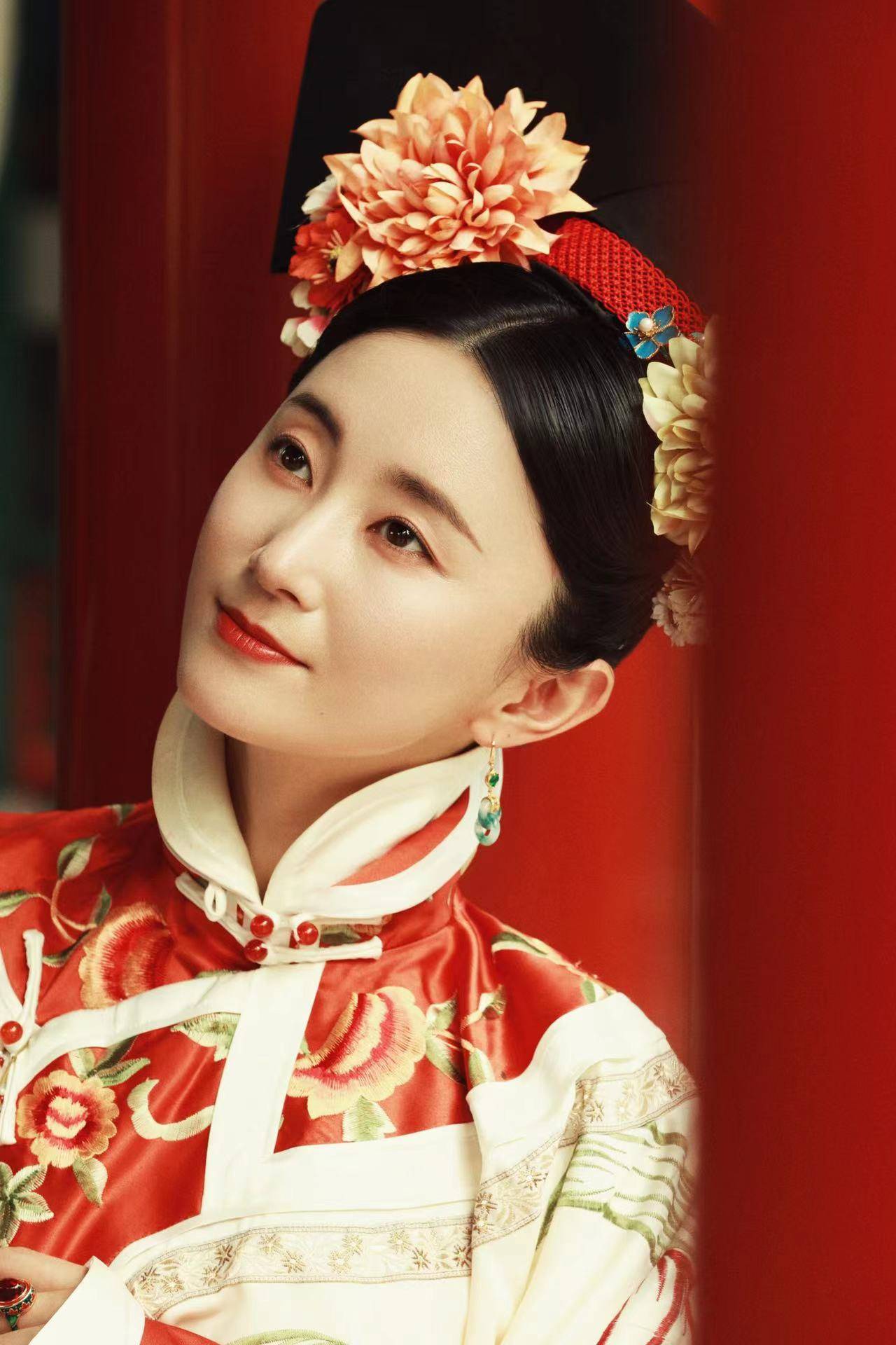 赵秦身着鲜红娇艳氅衣,旗头利落精美,护甲与戒指上的红色宝石相得益彰