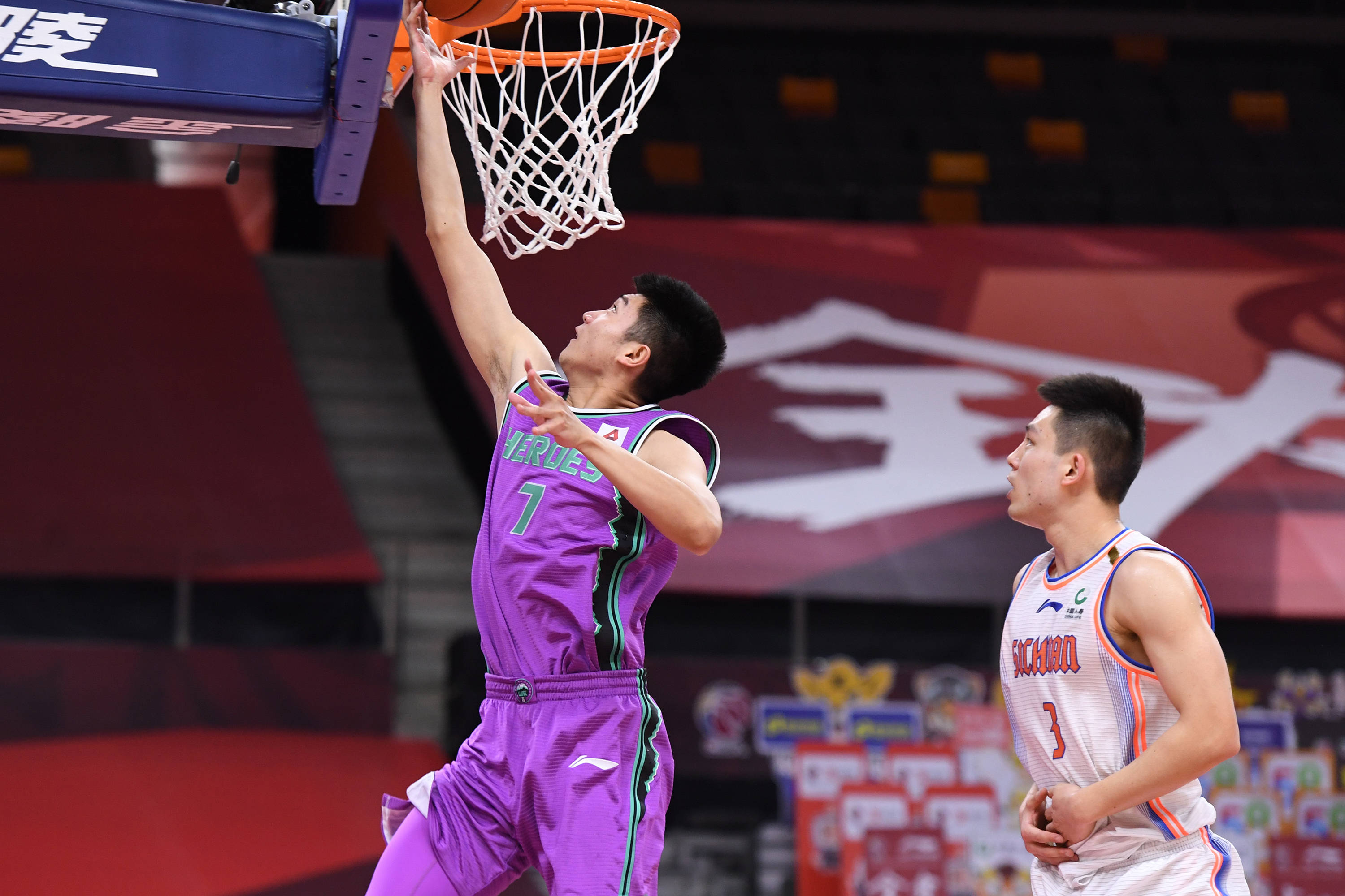 6月27日,山东西王队球员李泓翰(左)在比赛中上篮.