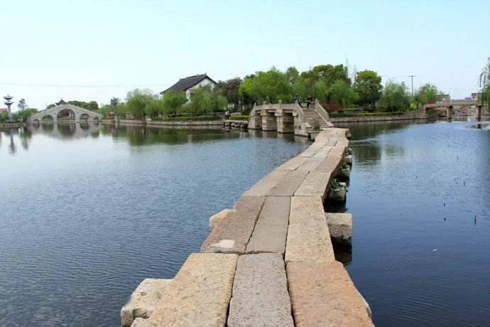 千里运河南北贯,乌蓬扁舟欸乃声.轻舟耕雪鱼跃腾,三长堤石桥撑伞人.