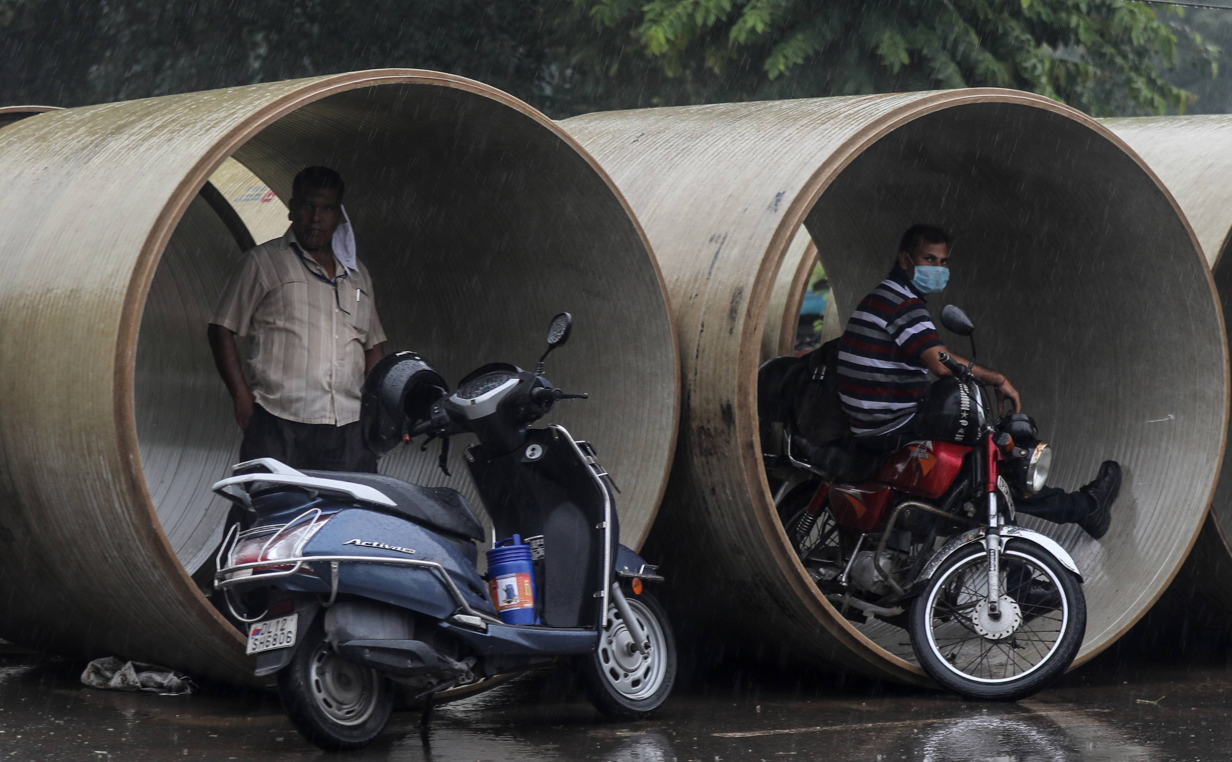 7月22日,在印度首都新德里,人们在水泥管中避雨. 新华社/欧新