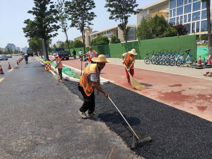 中润大道与西五路路口西侧施工人员正在铺设沥青.