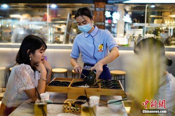 资料图:7月29日晚,云南昆明,一餐饮店服务员正在为顾客服务.