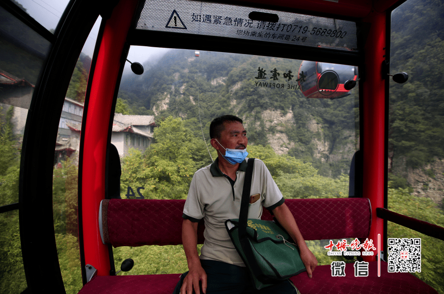 在云雾缭绕的武当山索道吊箱内,齐建国看着外面的风景稍作歇息,红润的