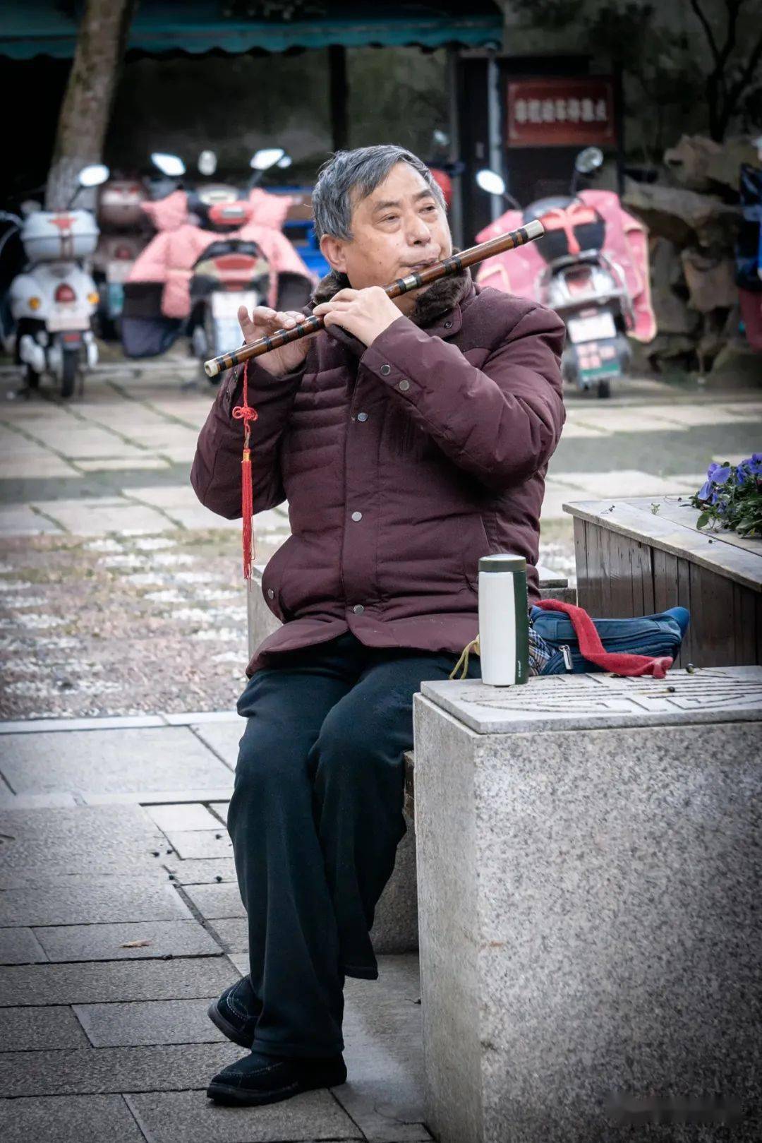 忙完家务的老人,在路边吹起笛子.