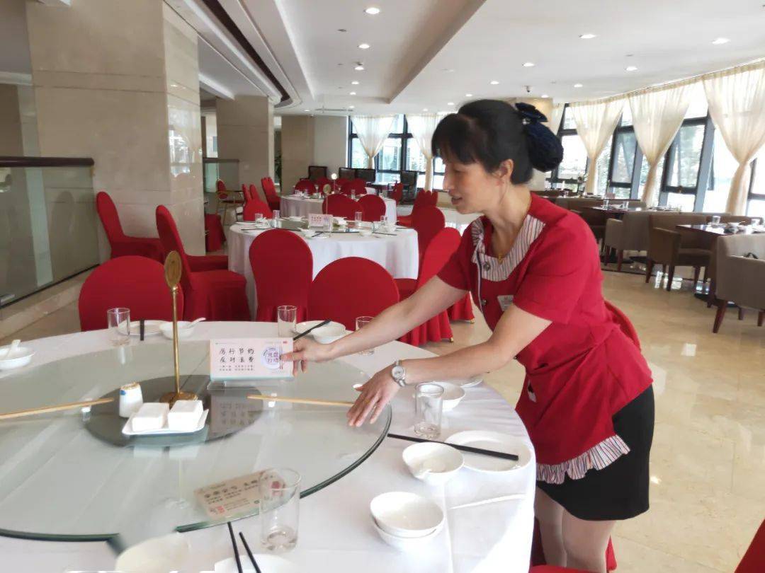 一位女士准备点菜时,酒店服务员在递过菜单,询问就餐人数后,温馨提示