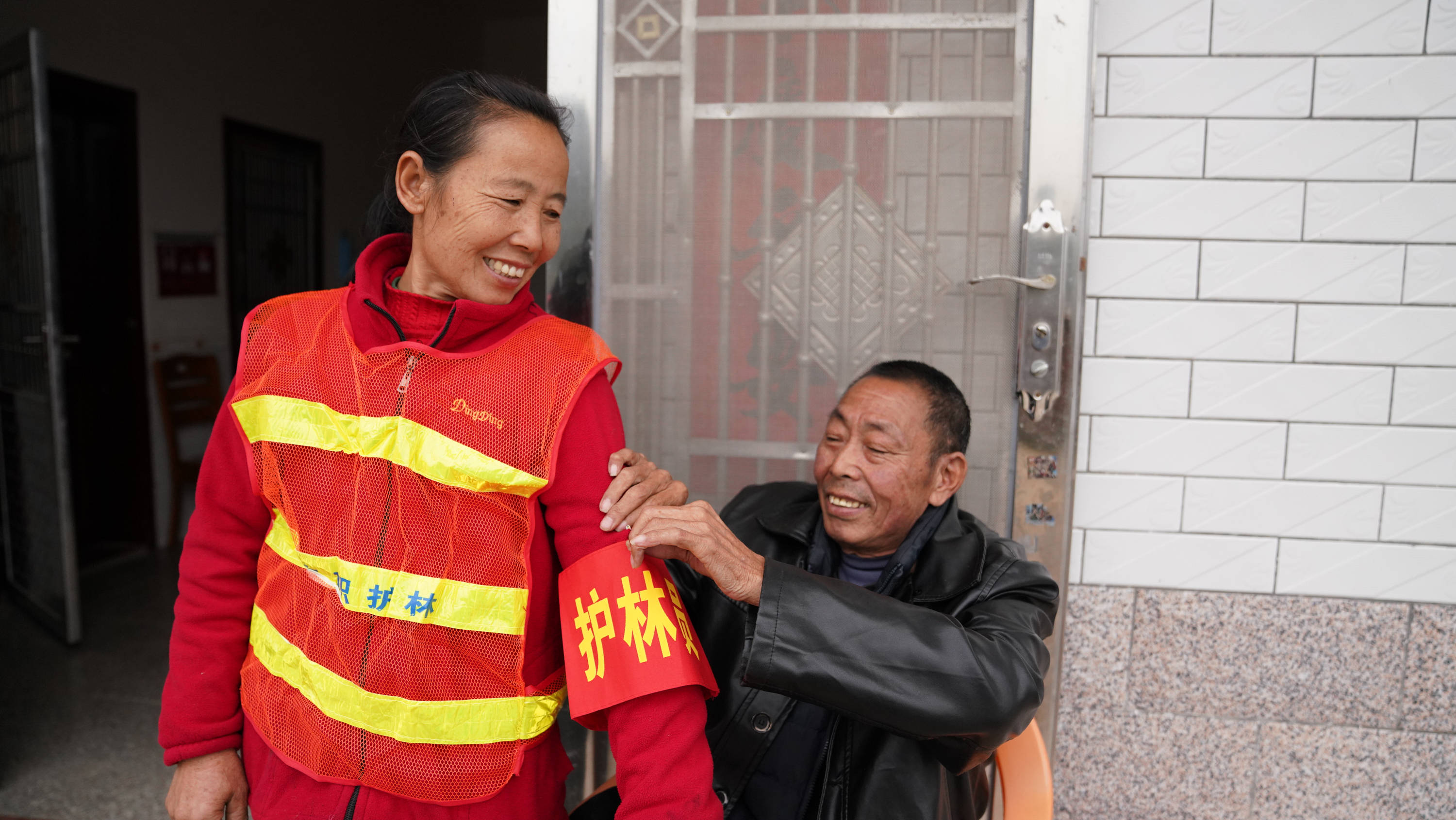 赖际林帮即将外出巡山的妻子刘仁香戴上护林员的袖标(1月22日摄.