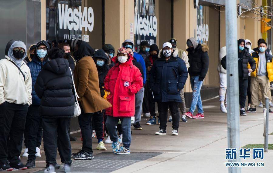3月8日,在加拿大多伦多,戴口罩的顾客在一家商店外排队等候.