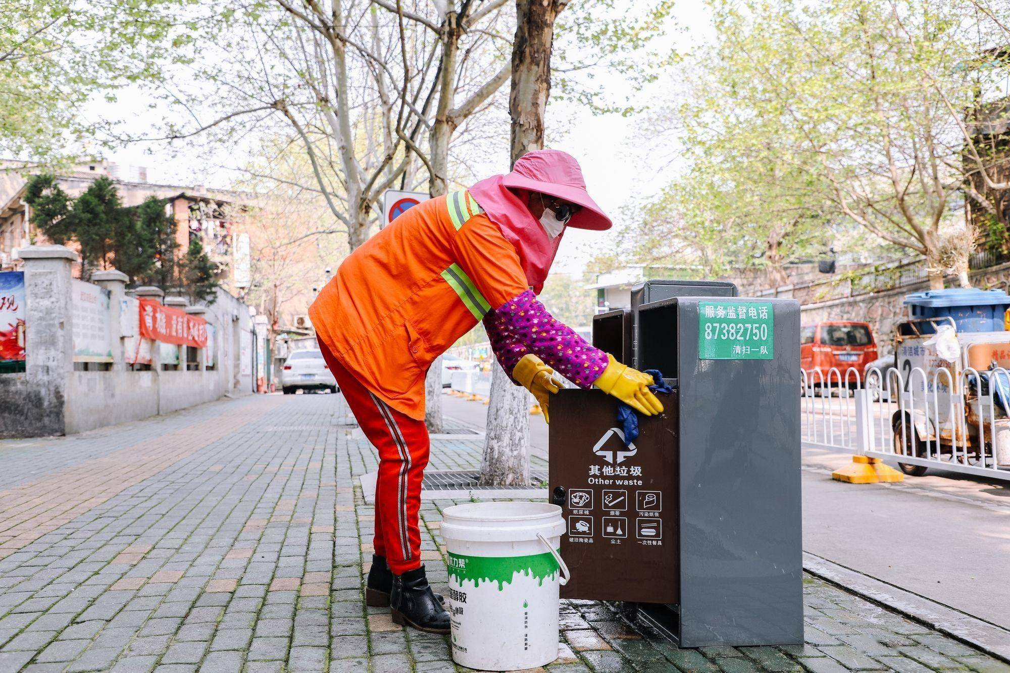 26日,环卫工张双镇巡回保洁,正在擦拭路边的果皮箱.通讯员刘洪凯 供图