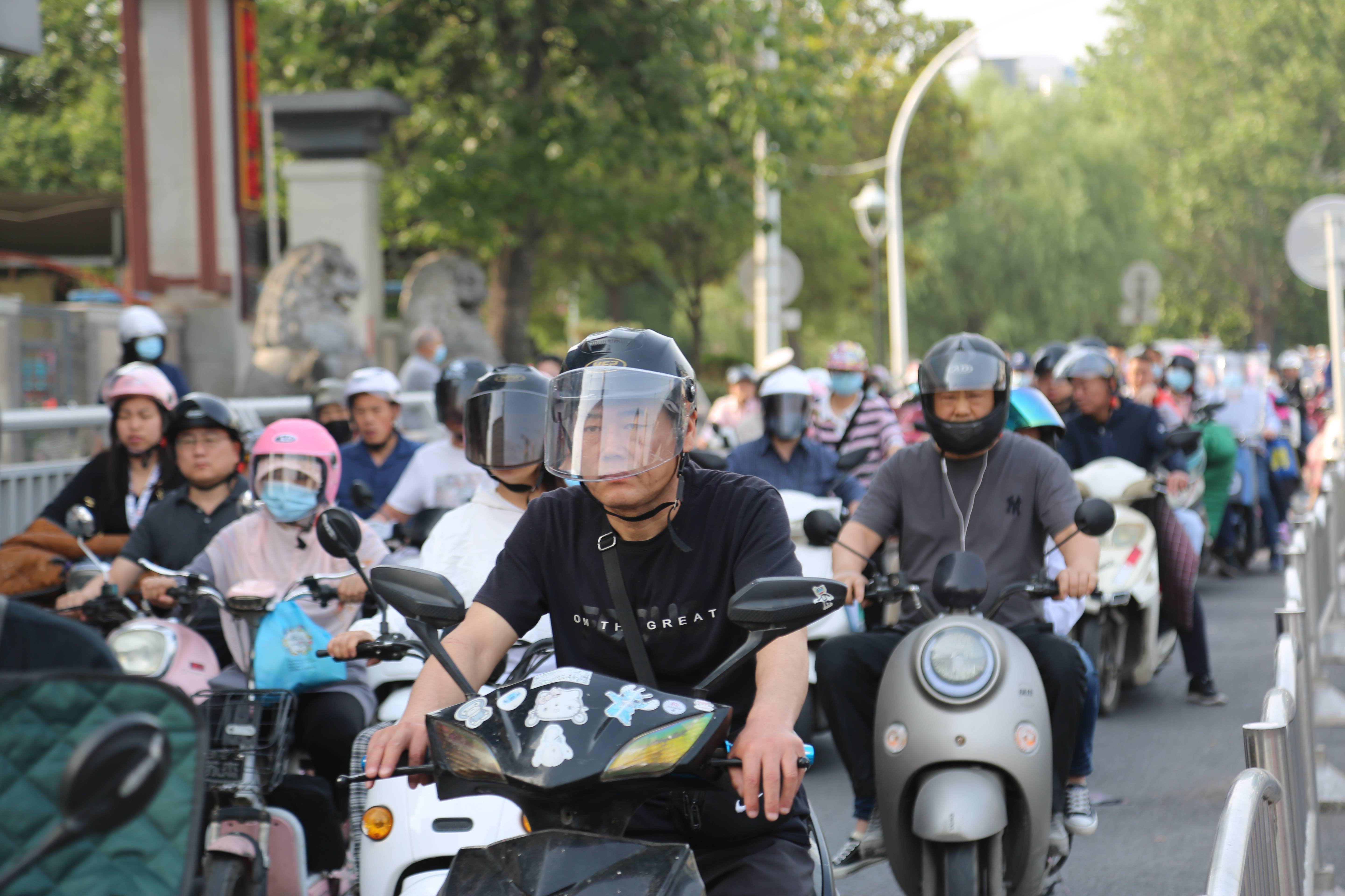 街头骑电动车戴头盔已成主流但不规范佩戴仍存在安全隐患