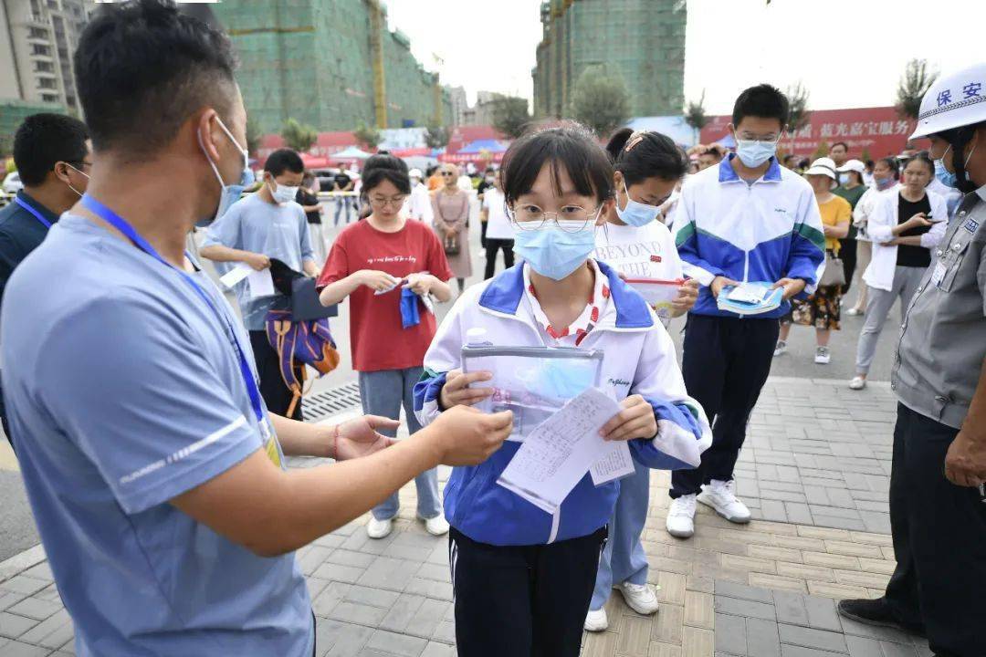 经过测温通道,正式进入考点按顺序走进学校大门考生们戴着口罩在老师