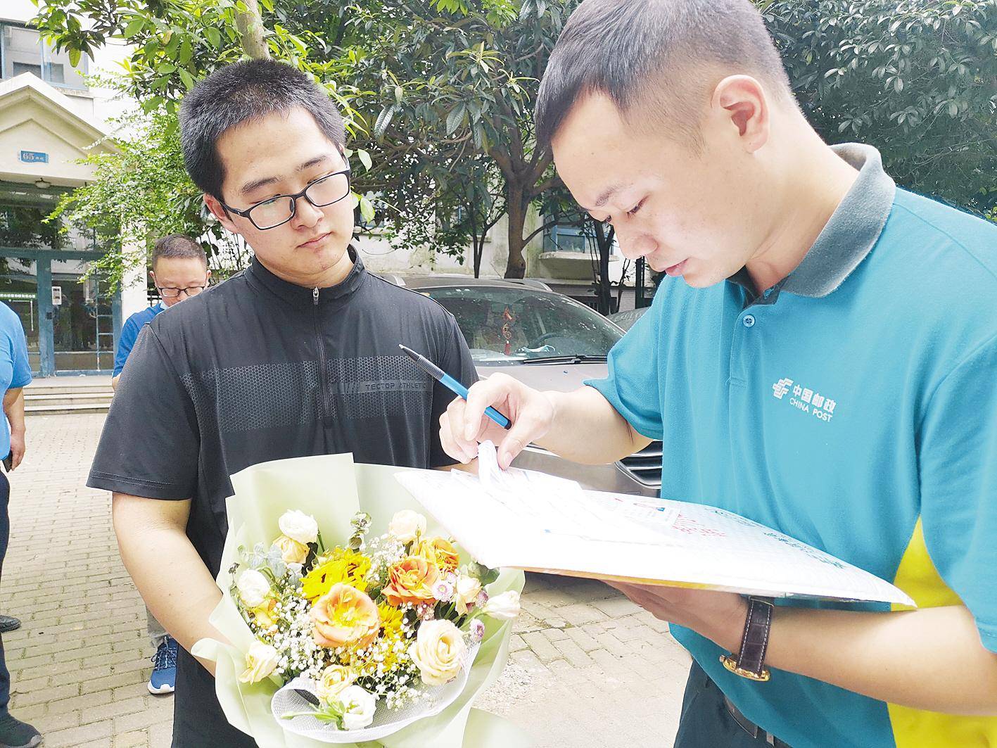 收件人严一腾(左)现场签收录取通知书(湖北日报全媒记者 左晨 摄)