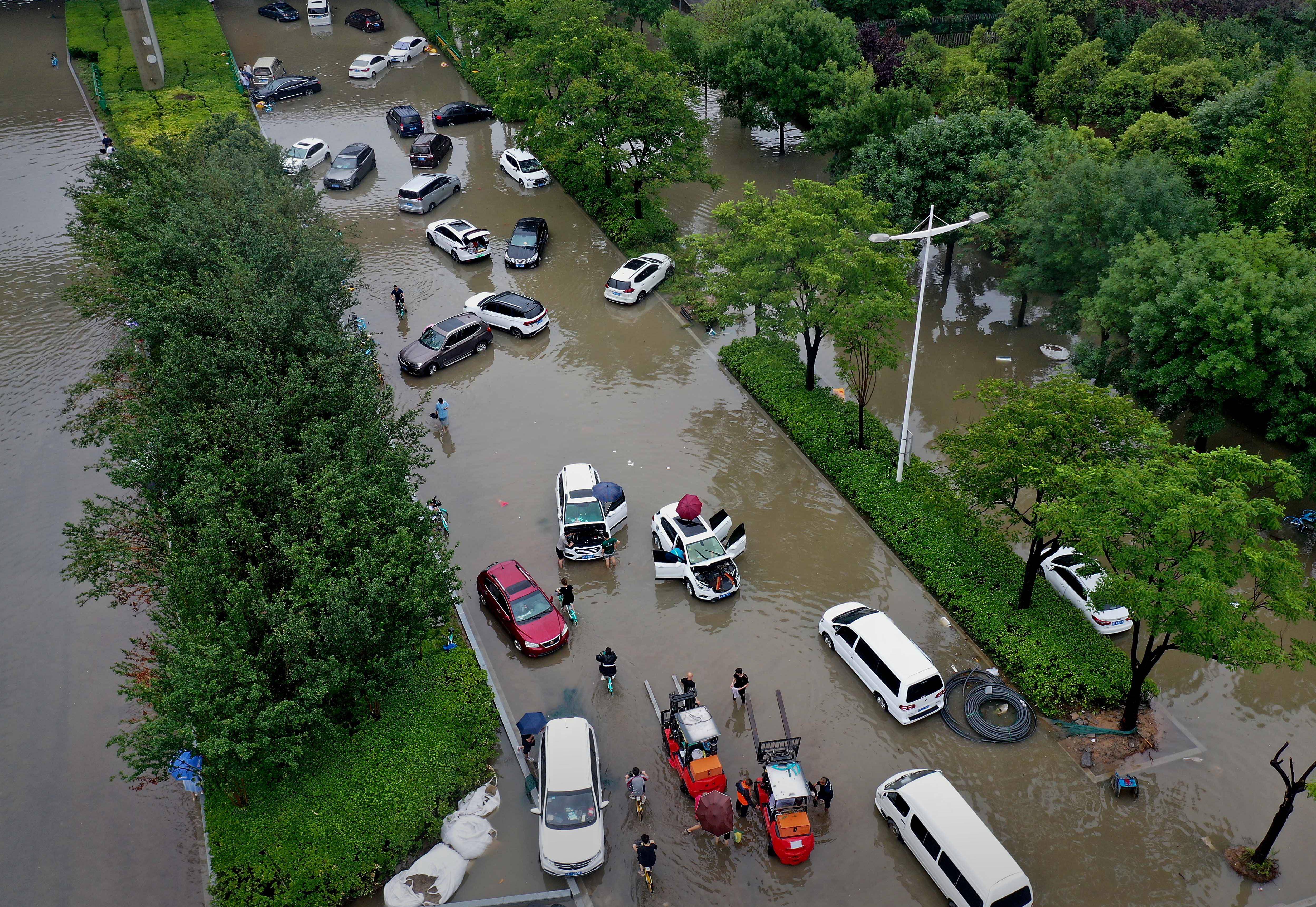 在河南省郑州市郑东新区一条道路上,市民和救援人员在清理被积水浸泡