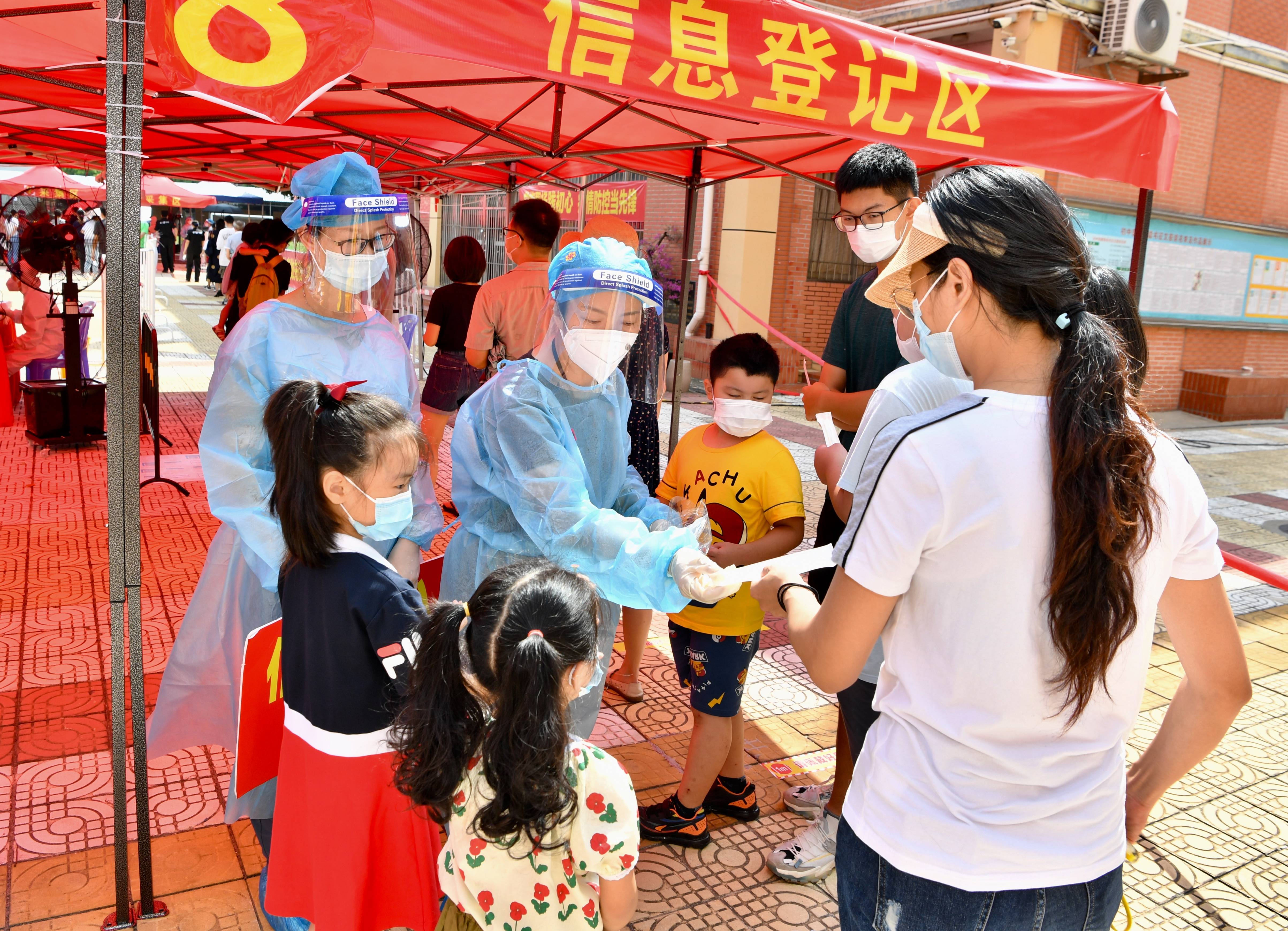 9月19日,在厦门松柏中学核酸检测点,志愿者为市民发放用于核酸检测